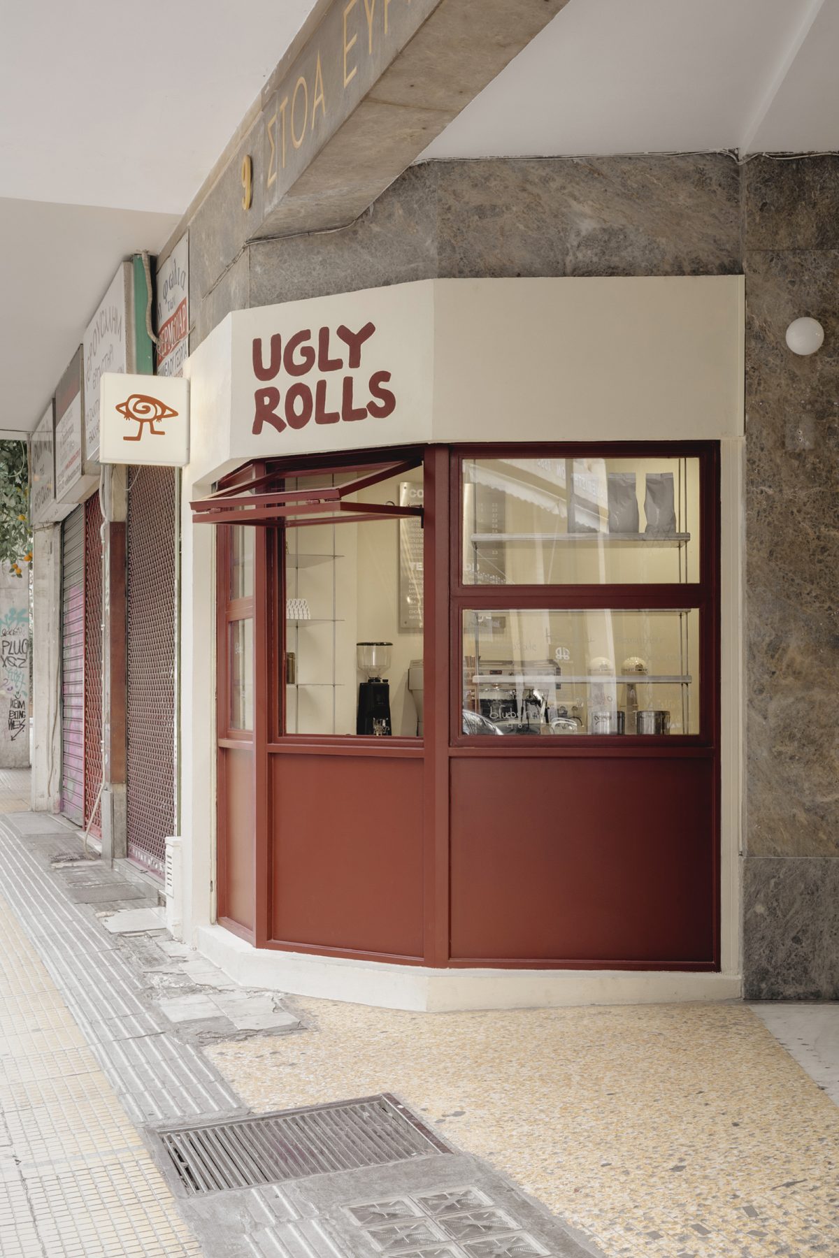 Archisearch Georgios Apostolopoulos designs Ugly Rolls, a tiny corner shop in Athens with cinnamon-toned maroon framing