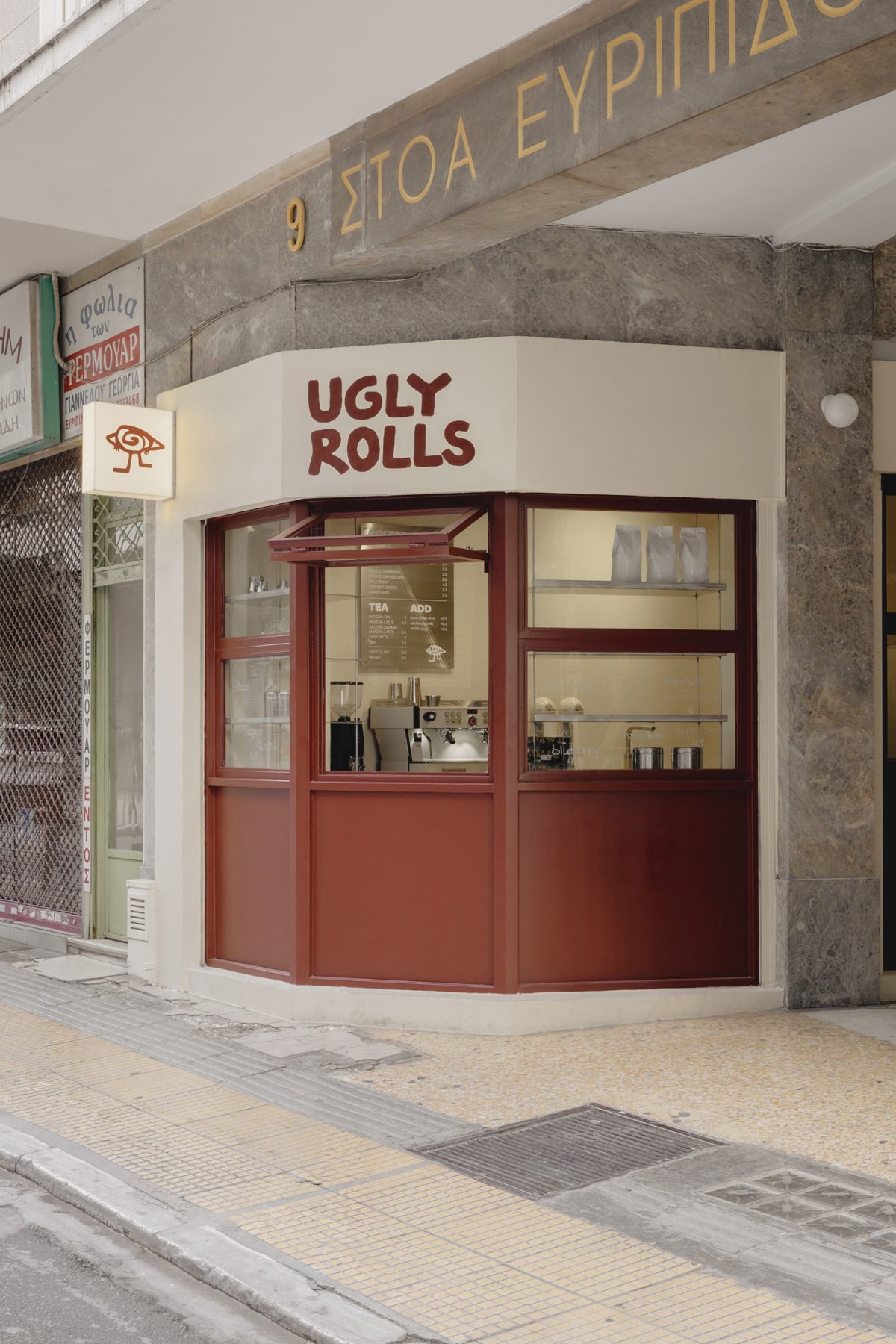 Archisearch Georgios Apostolopoulos designs Ugly Rolls, a tiny corner shop in Athens with cinnamon-toned maroon framing